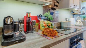 A kitchen with a coffee machine, utensils, and a flower arrangement on the counter. - 2 bedroom accommodation in Reedham (Reedham)