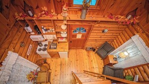 A cozy cabin interior with a wooden floor, a dining table, a kitchen area with a stove and sink, a small staircase, and a window with a view. - Ivy quaint tiny cabin creekside - Riverside Resort (Benton)