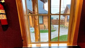 A window with a view of a wooden house and a lawn. - Cedar Mountain - Suite C (Grants Pass)