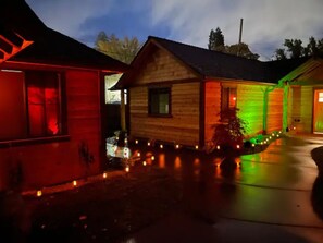 Uma cabana de madeira com varanda, iluminada por luzes coloridas.