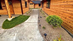 A row of wooden cabins with a concrete pathway and small shrubs. - Cedar Mountain - Suite C (Grants Pass)