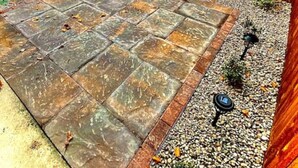 A paved patio area with stone tiles, surrounded by a wooden fence and small plants. - Cedar Mountain - Suite C (Grants Pass)