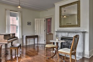 A room with a grand piano, a dining table with chairs, a fireplace, and a large mirror on the wall. - The Burrell House (Keene)