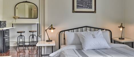 Une chambre à coucher comprenant un lit, deux tables de chevet avec des lampes, un bureau avec une chaise et un miroir.