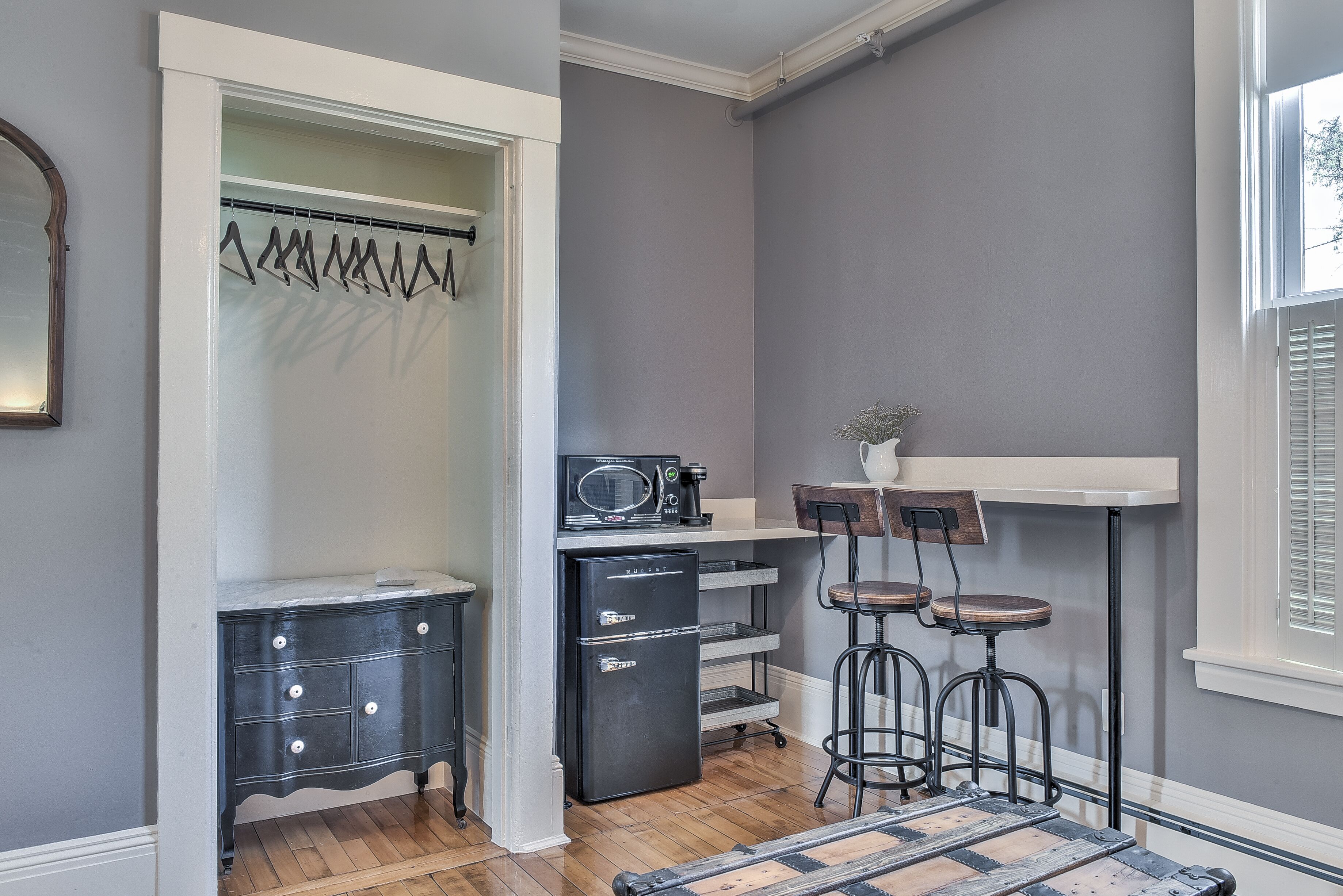 Una cocina compacta con refrigerador, microondas y taburetes de bar.
