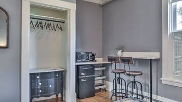 Una cocina compacta con refrigerador, microondas y taburetes de bar.