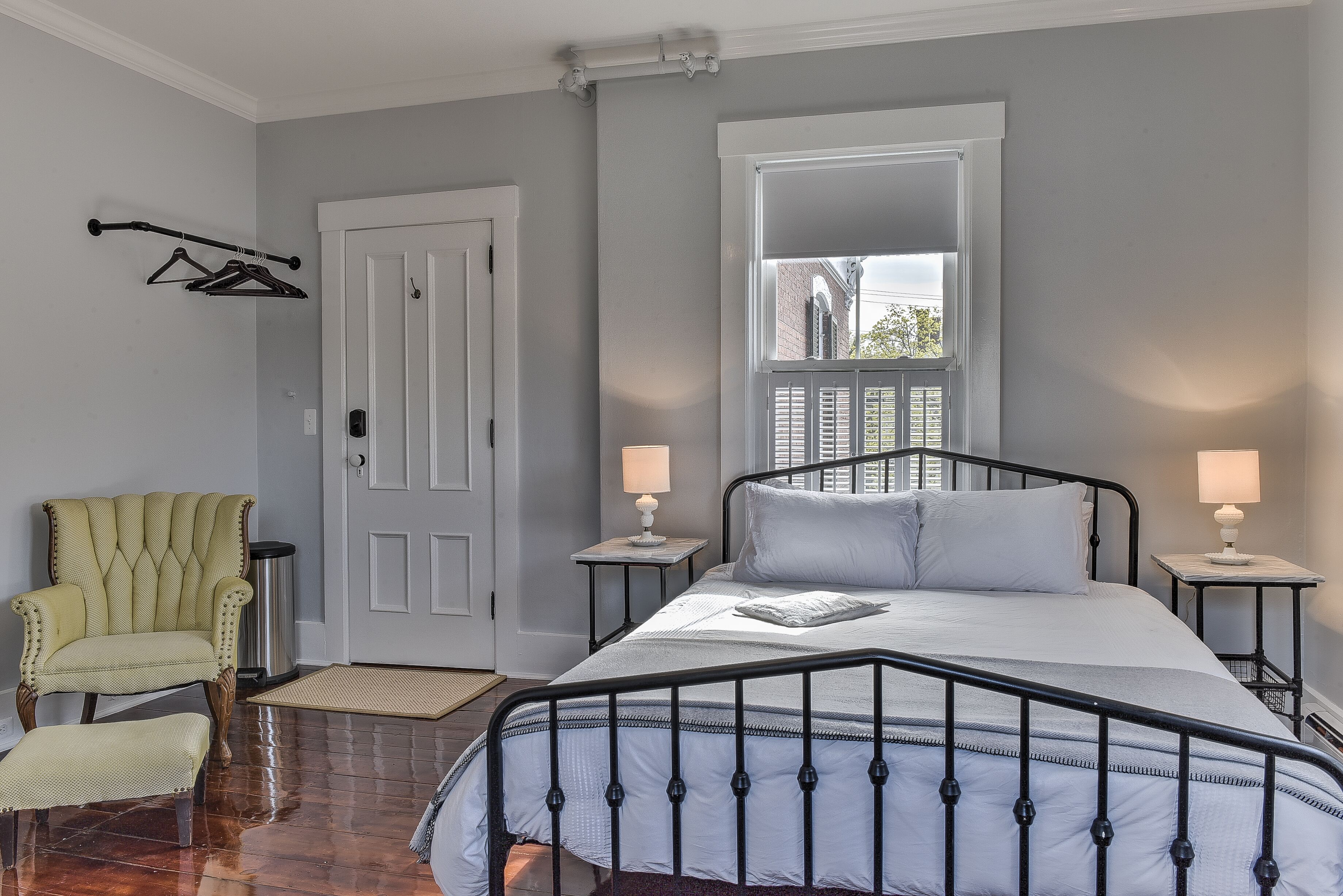 A bedroom with a bed, a chair, a door, and a window.