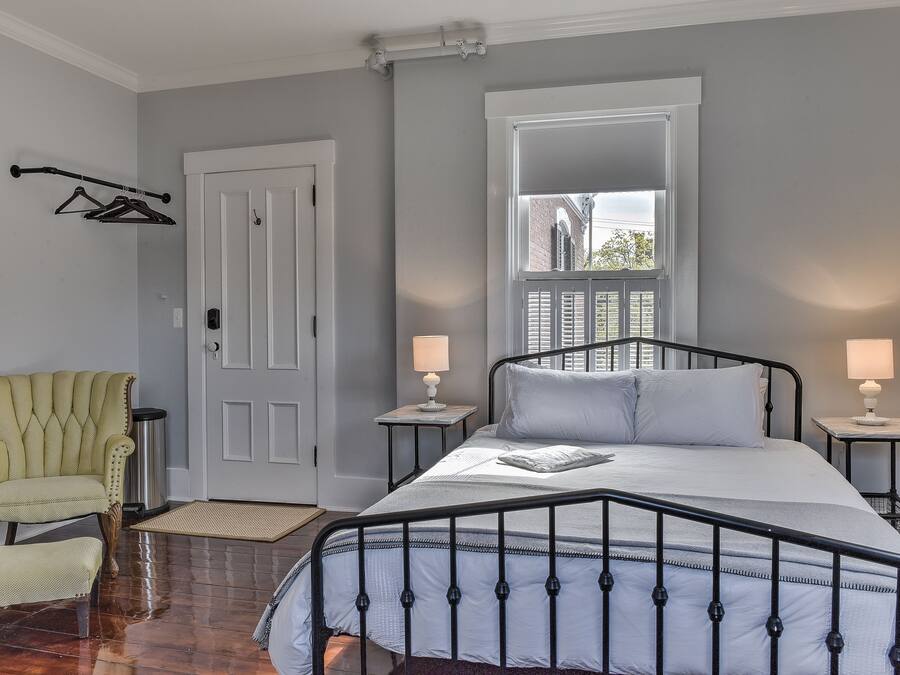 A bedroom with a bed, a chair, a door, and a window.