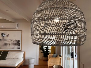 Un soggiorno moderno con un'ampia lampada intrecciata, un quadro appeso al muro, un divano e una poltrona.