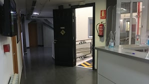 A corridor with a closed door, a fire extinguisher, and a bench. - Hostal Levante (Barcelona)
