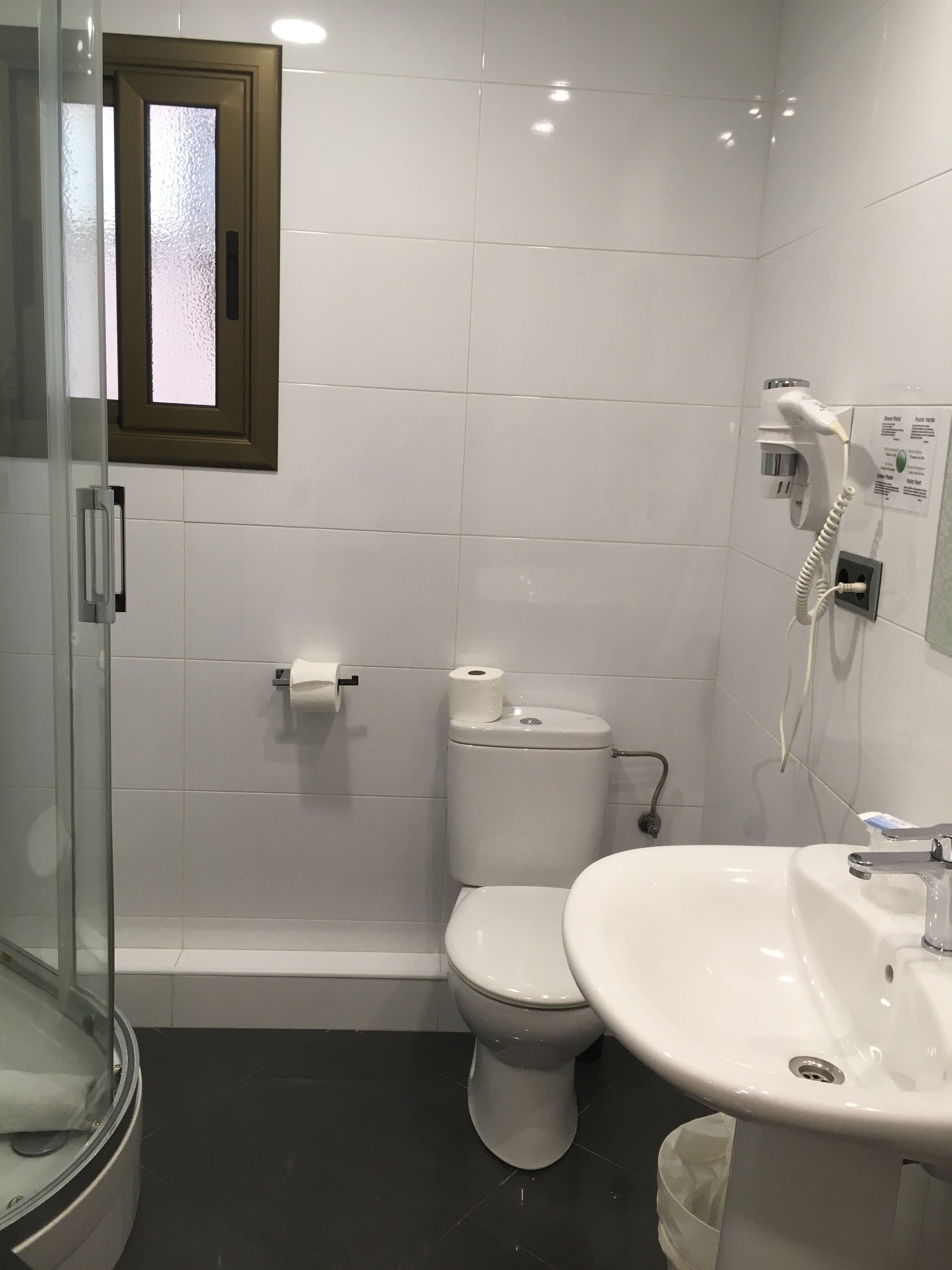 A bathroom with a toilet, sink, and shower area.