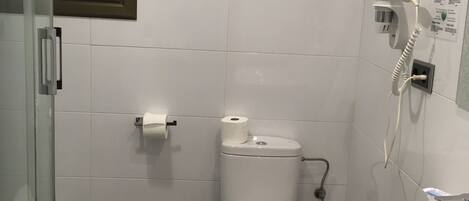Une salle de bain comprenant des toilettes, un lavabo et un espace douche.