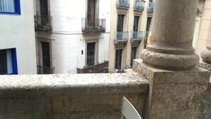 A stone balustrade with a metal chair, a white building with blue-framed windows, and a building with multiple balconies. - Hostal Levante (Barcelona)