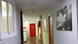 A hallway with a curved wall, a red door, and a framed picture on the wall. - Hostal Levante (Barcelona)