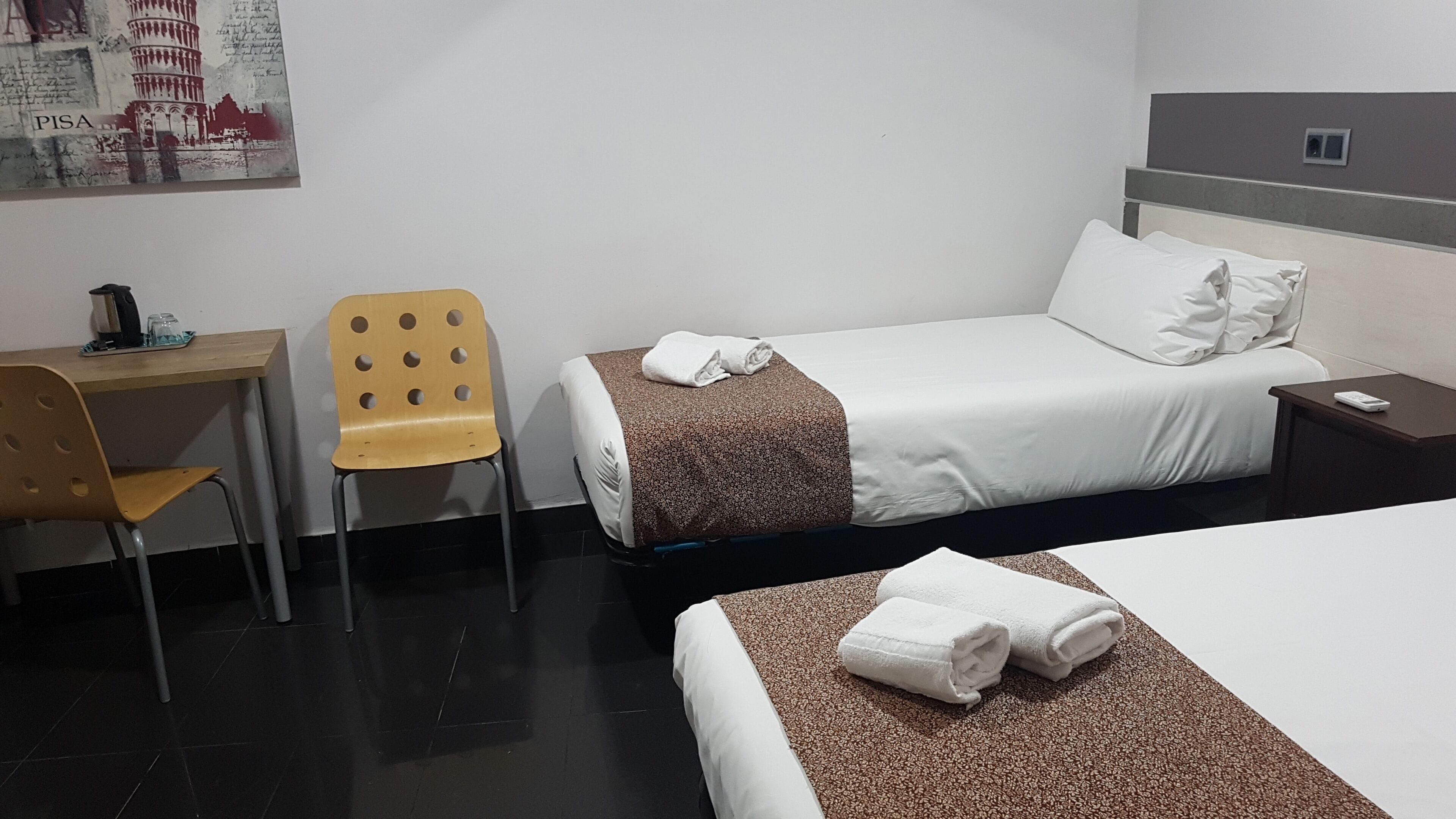Une chambre d’hôtel avec un lit, un bureau, une chaise et une table de chevet.