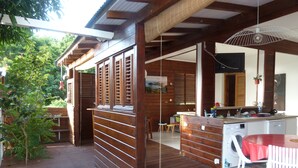 Una terraza de madera con zona de comedor, lavadora y cocina, que incluye un lavamanos y encimera.