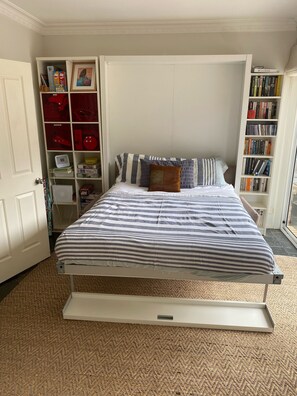 A bedroom with a bed, a bookshelf, and a door. - Somers Shack - walk to beach through Koala Reserve (Somers)