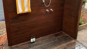 Une cabine de douche en bois, avec une serviette jaune et blanche à rayures accrochée à la porte.