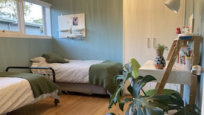 Une chambre avec deux lits, une table de chevet, une chaise, un bureau et une fenêtre.
