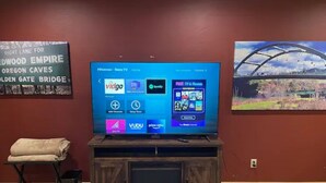 Ein Fernseher auf einem Holzboden mit einer digitalen Benutzeroberfläche, die verschiedene Streaming-Dienste anzeigt.