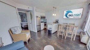 Una sala de estar moderna con un sofá, un comedor con mesa y sillas, una cocina con electrodomésticos y un cartel de Big Fish Rentals.