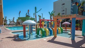 Zona de juegos infantiles con estructuras coloridas y una piscina.