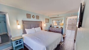 Un dormitorio con una cama grande, mesitas de noche, un aparador y un espejo.