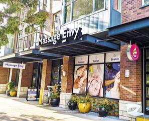 En massageterapi-klinik med et skilt der viser "Massage Envy" og et stort plakat, der reklamerer for behandlinger.