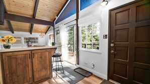 Une cuisine avec des meubles en bois, un coin bar et une grande fenêtre.