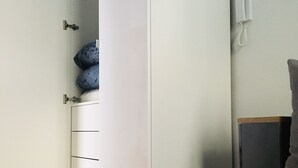 Ein Zimmer mit einem weißen Kleiderschrank, einem grauen Sofa und Holzboden.