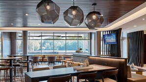 Un comedor moderno con un ventanal grande, varias mesas y lámparas contemporáneas.
