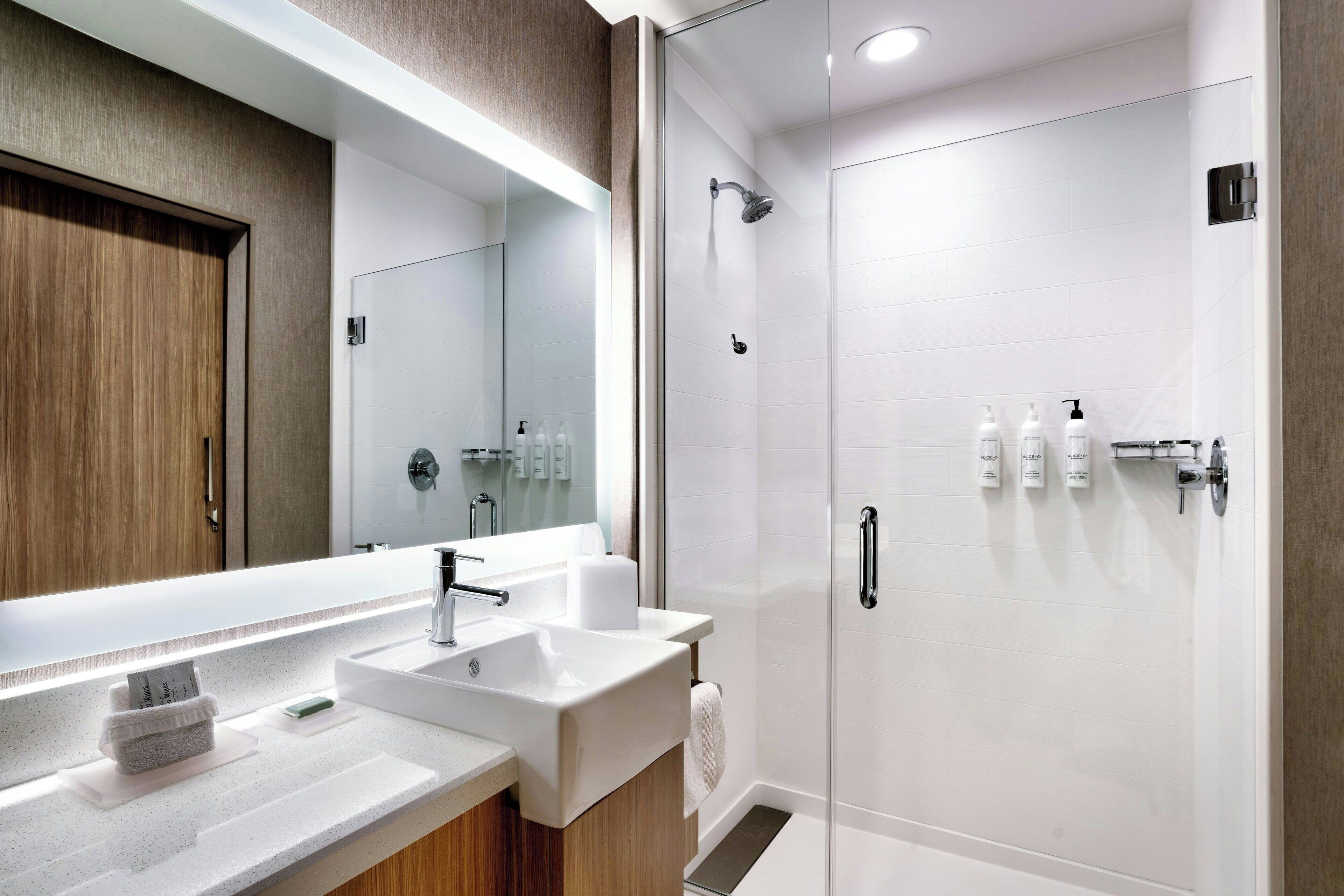 Un baño moderno con un espejo grande, un lavabo y una zona de ducha.