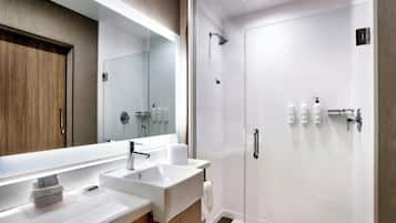 Un baño moderno con un espejo grande, un lavabo y una zona de ducha.
