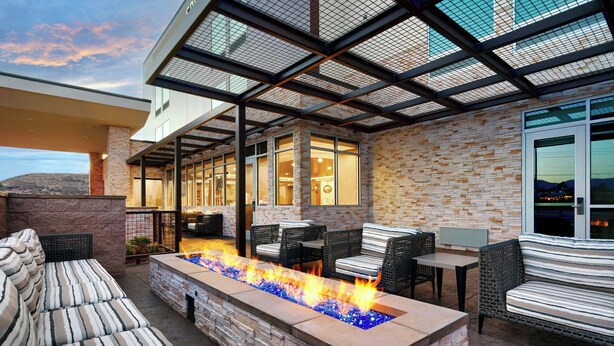Un patio exterior con una chimenea, asientos y vistas de la ciudad al anochecer.