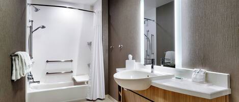 A modern bathroom with a bathtub, shower, vanity with a sink, and a large mirror.