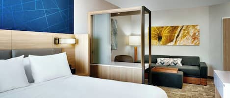 Una habitación de hotel con una cama grande, un escritorio, un sofá y un espejo.
