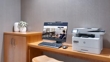 A wooden desk with a desktop computer, a printer, and a small stool.