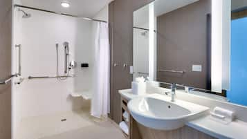 A modern bathroom with a walk-in shower, a large sink, and a mirror.
