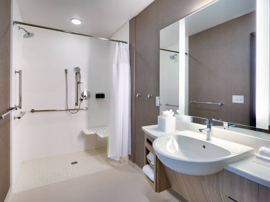 Un baño moderno con ducha a ras de suelo, lavamanos grande y espejo.