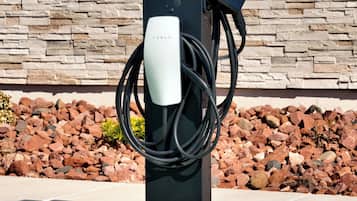 A Tesla charging station with a stone wall background.