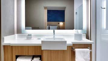 Un baño moderno con un espejo grande, un lavamanos blanco y un perchero para toallas.