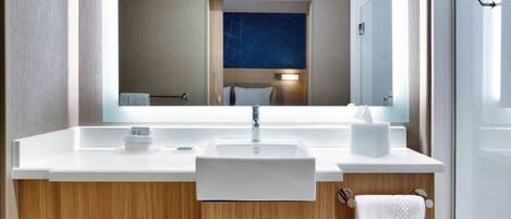 Un baño moderno con un espejo grande, un lavamanos blanco y un perchero para toallas.