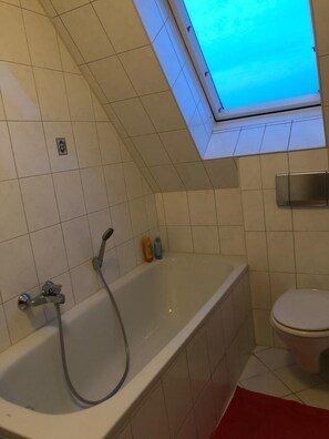 A bathroom with a bathtub, a toilet, and a skylight. - Flat for 7 ✭ Free cleaning every week ✭ TV&WIFI (Elsteraue)