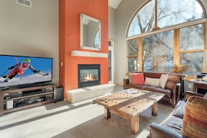 Relax in the living room with a large flat-screen TV, cozy fireplace, and comfortable seating area.