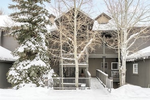 Guests can enjoy a covered porch and a balcony with a view of the surrounding snow-covered trees.