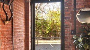 A brick-walled interior with a wooden reception desk, a black door leading outside, and a potted plant. - One-Of-A-Kind! Roll Up Garage Door, Pool, Speakeasy (Nashville)