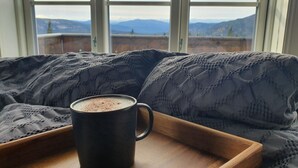 A cozy seating area with a black mug on a wooden tray, a window with a view of mountains and a cloudy sky. - Beautiful Mountaincabin at Lifjell (Vestfold og Telemark)
