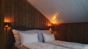 A double bed with white bedding in a room with wooden walls and sloped ceilings. - Beautiful Mountaincabin at Lifjell (Vestfold og Telemark)