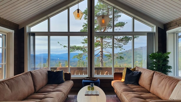 A cozy room with two leather sofas facing a large window overlooking mountains. - Beautiful Mountaincabin at Lifjell (Vestfold og Telemark)