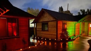 A wooden cabin with a porch, illuminated by colorful lights. - Cedar Mountain - Suite E (Grants Pass)